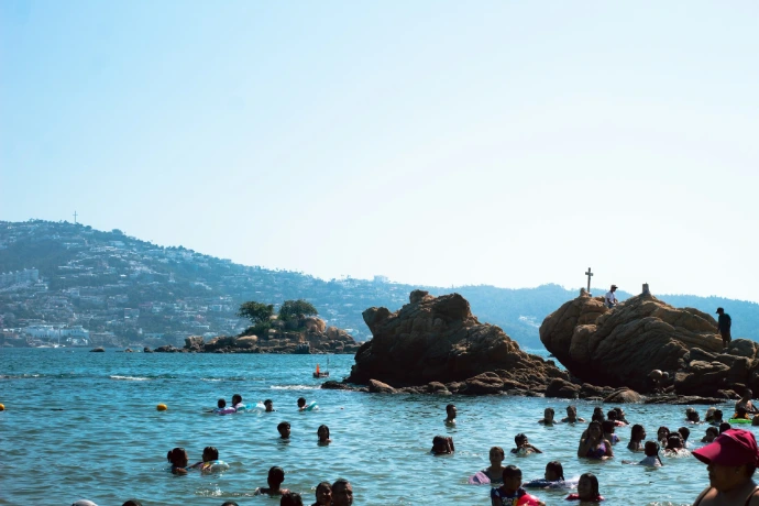 People swimming in the ocean near rocky shore